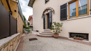 A courtyard with a stone wall, a potted plant, outdoor furniture, and a staircase leading to a door. - Holiday Apartment 'New Casa Ilaria' near Center with Garden & Wi-Fi (Torri del Benaco)