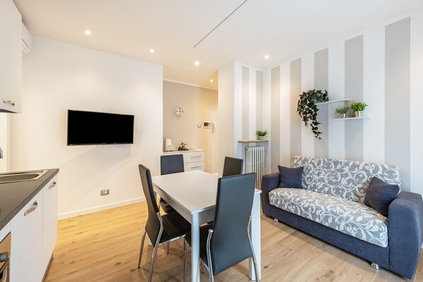 Un espacio habitable moderno con comedor, sofá y televisor de pantalla plana.