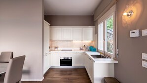 Een moderne keuken met witte kasten, een inbouwoven en een raam met uitzicht op groen.
