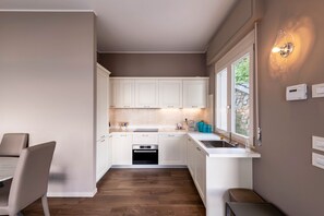Una cocina moderna con armarios blancos, horno integrado y ventana con vistas a zonas verdes.