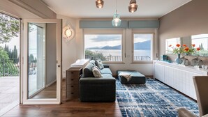 Een moderne woonkamer met een bank, poef en uitzicht op de omgeving.