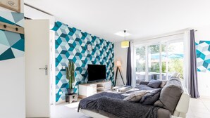 Un dormitorio moderno con una cama, televisión, escritorio y un amplio ventanal.