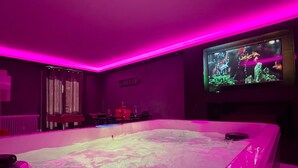 A room with a large hot tub, a television screen, and a sign that reads 'NIGHT SAIL LOVE'. - Holiday Home 'La Casa De Lové Suite Jacuzzi' with Private Garden and Wi-Fi (Melun)