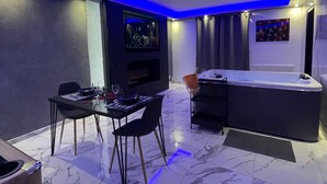 A modern room with a dining table, chairs, a TV, a hot tub, and a fireplace. - Holiday Home 'La Casa De Lové Suite Jacuzzi' with Private Garden and Wi-Fi (Melun)