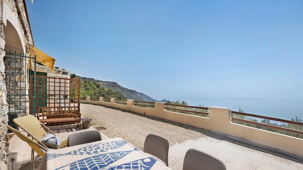 A terrace with a table and chairs, a wooden bench, and a view of the sea. - Apartment "Oleandro" with Sea View, Garden & Wi-Fi (Finale Ligure)