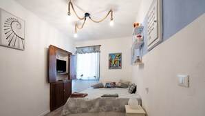 Une chambre à coucher avec un lit, une télévision, un bureau et une fenêtre avec des rideaux.