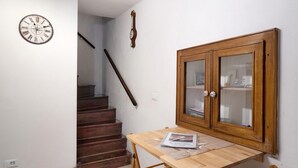 Un escalier menant à un palier où se trouvent une table en bois et un meuble avec des portes en verre.