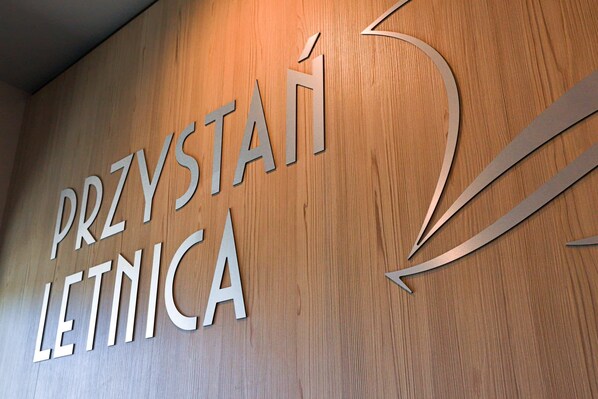 The entrance to the residential building, featuring the "Przystań Letnica" sign. The polished wooden details add elegance to the design.