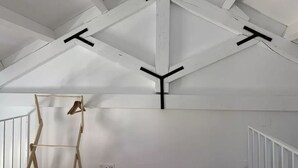 Une pièce aux murs blancs et dont le plafond est constitué d’une structure en bois.