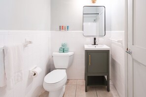 Baño con inodoro, lavabo, espejo y papel higiénico.
