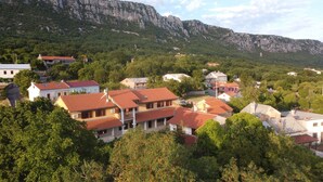 Un barrio residencial con casas de tejados rojos, rodeado de exuberante vegetación y montañas al fondo.