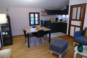 Un ambiente compatto con tavolo e sedie, divano e angolo cottura.