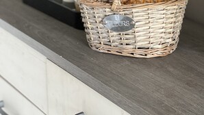 A wicker basket with a label on a wooden counter, containing two pineapples. - Bungalow for 2 - Ocean View (Saint Paul)