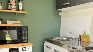 A compact kitchen with a washing machine, microwave, and sink. - Bungalow for 2 - Ocean View (Saint Paul)