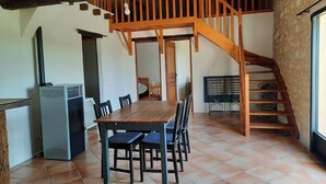 Ein rustikaler Essbereich mit Holztisch und -stühlen, einer Treppe und einer kleinen Küchenzeile inklusive Klimaanlage.