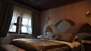 A bedroom with a large bed, a bench, a nightstand, and a window with curtains. - Arasta Konak Otel (Eskisehir)