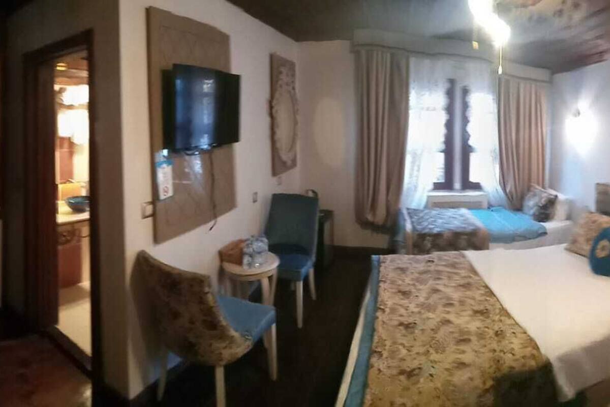 A hotel room with two beds, a TV, a desk, and a chair.