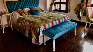 A bed with a tufted headboard, a colorful blanket, and a matching bench. - Arasta Konak Otel (Eskisehir)