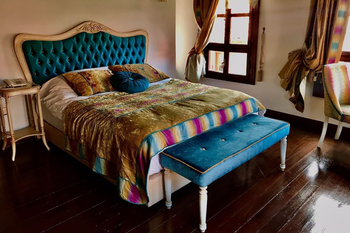 A bed with a tufted headboard, a colorful blanket, and a matching bench.