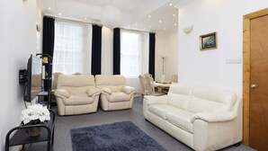 A living room with two beige sofas, a coffee table, a TV, and a blue rug.