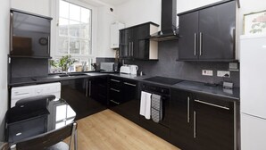 A modern kitchen with dark cabinetry, a built-in oven, and a window providing natural light.