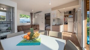 A modern, compact living space with a dining area, kitchenette, and a cozy seating area. - EuroParcs Hermagor  Nassfeld (Hermagor-Pressegger See)