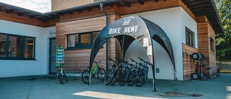 A bike rental station with multiple bicycles parked under a canopy.