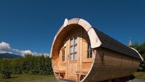A wooden cabin with a curved roof, a door, and windows. - EuroParcs Hermagor  Nassfeld (Hermagor-Pressegger See)