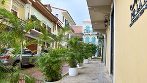 A narrow street lined with potted plants and parked cars, leading to a building with a sign reading "PH-LAM". - Apartment in the Heart of Casco Viejo Panama 11 (Panamá)