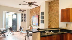 A kitchen with a stone backsplash, wooden cabinets, a black countertop, and a ceiling fan. - Apartment in the Heart of Casco Viejo Panama 11 (Panamá)