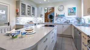 A modern kitchen with a large island, white cabinetry, and a clock on the wall.