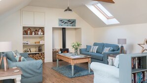 A cozy loft-style living room with a sloped ceiling, a fireplace, and a skylight.