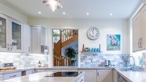 A modern kitchen with a central island, a built-in oven, and a stainless steel sink.