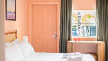 A hotel room with a bed, a window with curtains, a bedside table, and a ceiling light fixture.