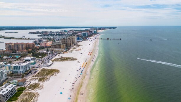 An aerial view of a coastal city with a long sandy beach, a pier extending into the water, and a mix of high-rise and mid-rise buildings along the shore. - 123 · ☀Pool✔ Beach✔ Self Checkin✔ Free Parking✔ (Clearwater)