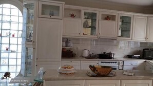Una cocina con armarios blancos, microondas, tetera y ventana con vistas.