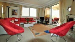 Una sala de estar con un sofá rojo, dos sillones rojos, una mesa de centro y un televisor.