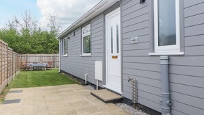 Una propiedad residencial con fachada gris, una puerta blanca y un pequeño jardín delantero con patio.