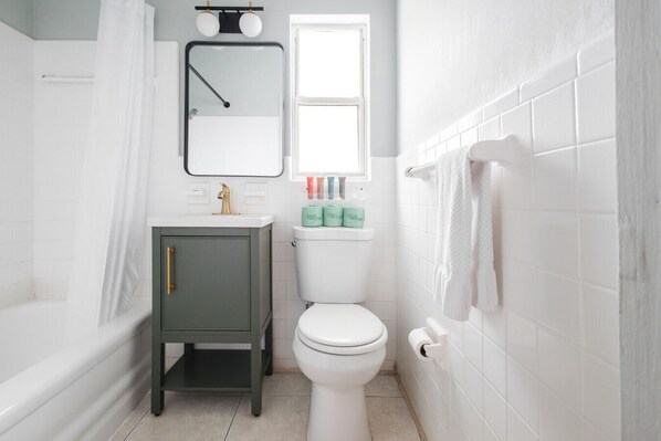 Un baño con bañera, inodoro, tocador y ventana.