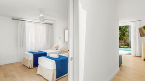 Ein Hotelzimmer mit zwei Betten, einem Deckenventilator und Blick auf den Swimmingpool.