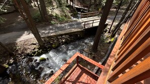 Eine Holterrasse mit Blick auf einen Bach, eine Steinbrücke und einen gepflasterten Weg.