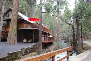 Eine Lodge mit einer Holzterrasse, Sitzgelegenheiten im Freien und Blick auf ein bewaldetes Gebiet.