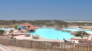 A large swimming pool with a wooden deck and lounge chairs, surrounded by a wooden fence.