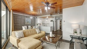 A modern living room with a sectional sofa, a wooden coffee table, and a ceiling fan.
