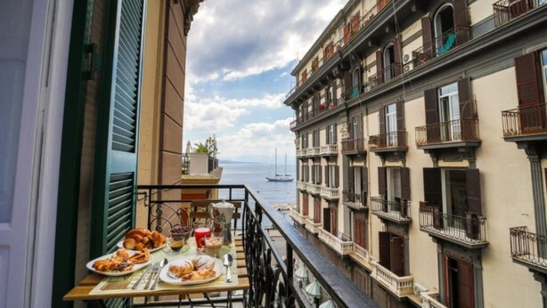A balcony with a table set for breakfast overlooking a marina with boats. - Di Palma Suite Museum (Napoli)