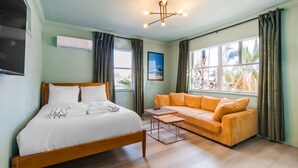 A room with a bed, a sofa, a small table, and a window with curtains. - 127 · ☀Pool✔ Kitchen✔ Beach✔ Self Checkin✔ Free Parking✔ (Clearwater)