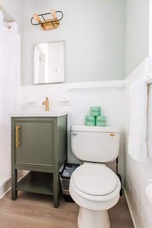 A bathroom with a green vanity, a white toilet, and a mirror above the sink.