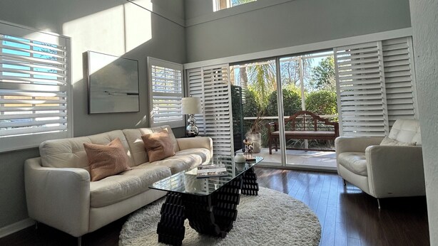 A spacious living room with a large window, a sofa, a coffee table, and a fireplace. - US Open Pickleball Stay - 3 Masters - Walkable Location (Naples)