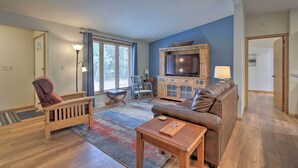A living room with a brown leather couch, wooden coffee table, and a TV stand with a flat-screen TV. - Rhinelander Home - Jennie Webber Lake On-Site (Rhinelander)