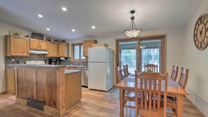 A kitchen with wooden cabinets, a central island, a dining table with chairs, and a large clock on the wall. - Rhinelander Home - Jennie Webber Lake On-Site (Rhinelander)